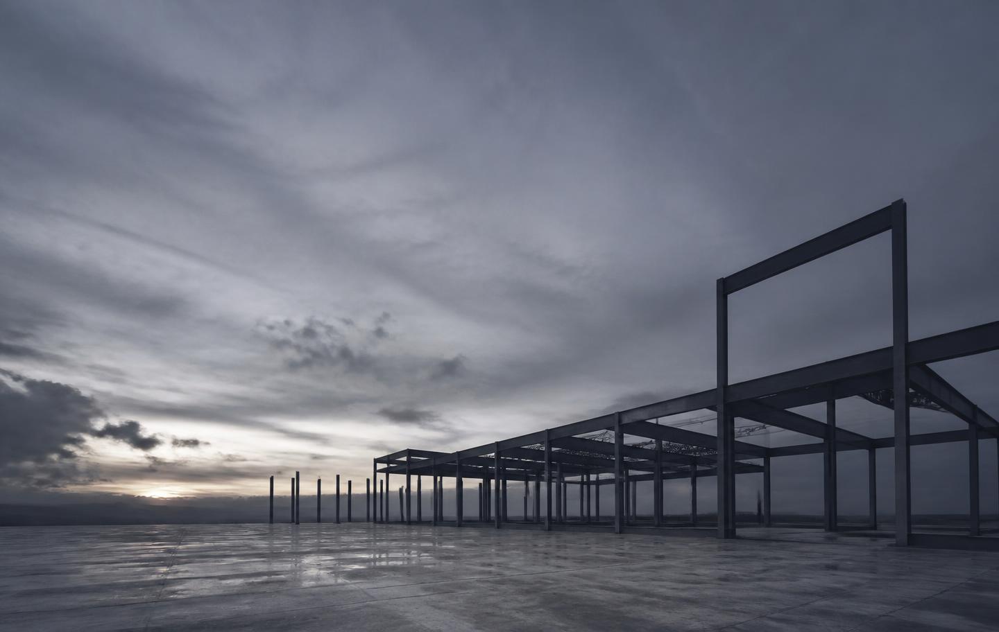 Steel frame rising over a finished foundation at dusk